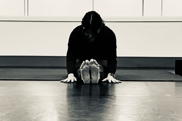 Black and white photo of a person doing yoga in a studio.