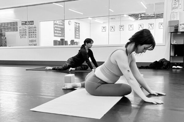 Black and white photo of two people doing yoga in a studio.