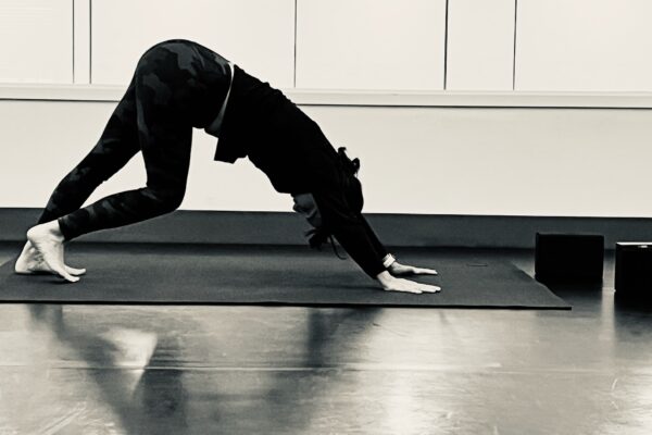 Black and white photo of a person doing yoga in a studio.