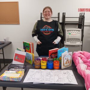 Julia with books wearing Ken's Gym apron